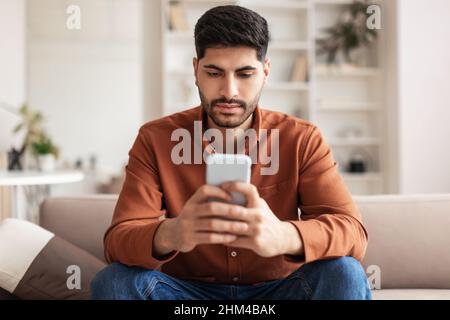 Jeune homme arabe utilisant un smartphone à la maison Banque D'Images