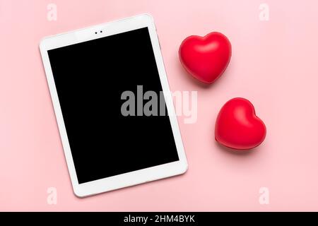 Tablette pour choisir des cadeaux, fait l'achat, deux coeurs rouges sur table rose vue du dessus plat Lay liste d'achats de vacances, bonne Saint-Valentin, fête, en ligne Banque D'Images
