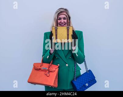 Londres 08 Fév 2022 modèle Holding (r) a Royal Blue courtepointe lambeau classique double rabat Chanel, 2019, estimation £ 3 000 – 5 000 (L)Orange H Ostrich Birking 30 Hermès, 2002, estimation £8 000 – 12 000.(C) Un sac à poignée en cuir jaune, Bottega Veneta, début 2000s, £200 - 300 Quezada-Neiman/Alay Live News (C) Banque D'Images