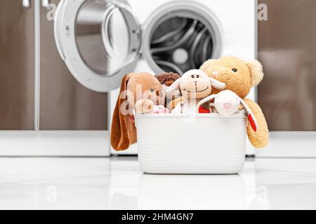 Jouets pour enfants dans un panier à l'arrière-plan d'une machine à laver. Banque D'Images