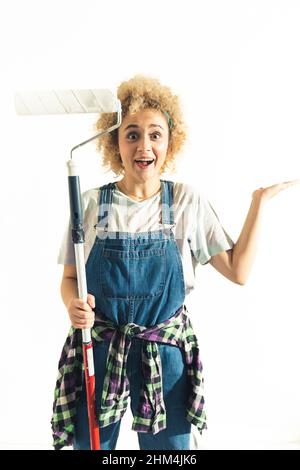 Drôle fille posant avec rouleau de peinture - isolé sur fond blanc. Photo de haute qualité Banque D'Images