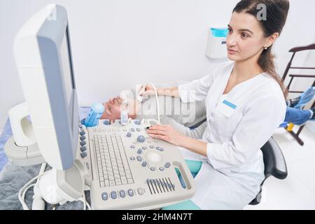 Diagnosticien concentré effectuant une échographie de la glande thyroïde Banque D'Images