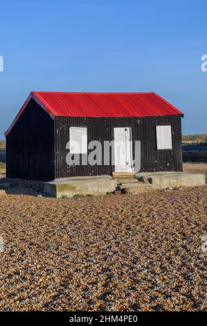 Cabane au toit rouge à Rye Harbour, Sussex, Royaume-Uni, sous le soleil d'hiver tôt le matin Banque D'Images