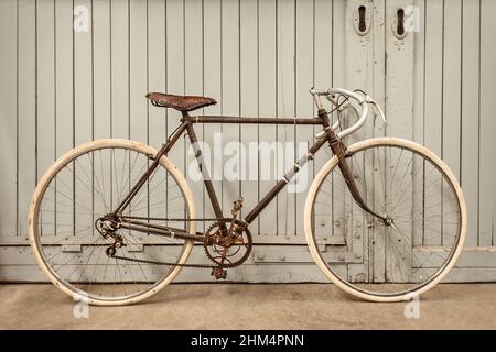 Vélo de course rouillé d'époque stationné dans une ancienne usine avec des portes en bois Banque D'Images