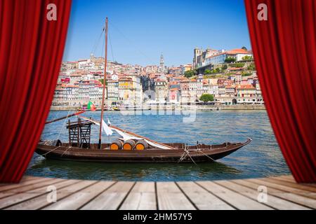 Des rideaux rouges de théâtre ouvert contre un bateau portugais typique en bois, appelé 'barcos rabelos', utilisé dans le passé pour transporter le célèbre vin de port (Port Banque D'Images