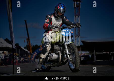 11-05-2021 Riga, Lettonie beau cavalier homme avec la barbe et la moustache en cuir noir veste de moto et lunettes de soleil assis sur le style classique café voiture de course Banque D'Images