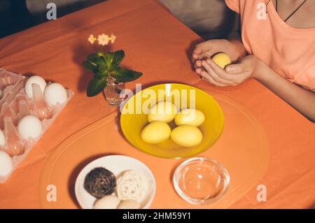 Fille peint des oeufs de pâques avec des peintures à l'aquarelle en jaune Banque D'Images