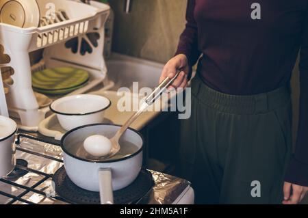 Cuisson des oeufs dans une louche émaillée pour la coloration pour pâques Banque D'Images