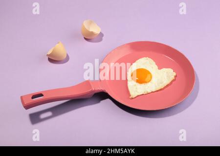 Poêle à frire rose et œuf en forme de coeur. Saint Valentin Banque D'Images