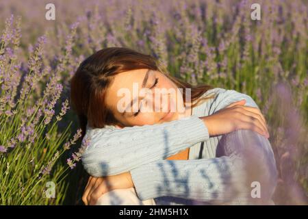 Bonne femme se détendant avec les yeux fermés assis dans le champ de lavande Banque D'Images