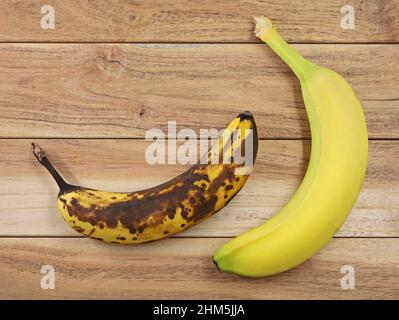 Vue de dessus de la banane brune surmûre et mûre jaune sur fond de bois, comparaison des bananes Banque D'Images