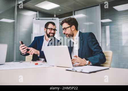 Homme d'affaires souriant qui a fait des nouvelles amusantes à son collègue lors d'une réunion d'affaires Banque D'Images