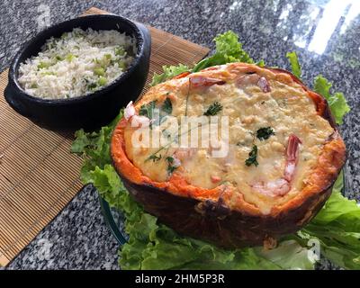 Crevettes à la citrouille (Camarao na Moranga) - crevettes à la sauce crémeuse au lait de coco servies à l'intérieur d'une citrouille rôtie. Banque D'Images