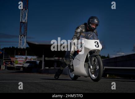 11-05-2021 Riga, Lettonie beau cavalier homme avec la barbe et la moustache en cuir noir veste de moto et lunettes de soleil assis sur le style classique café voiture de course Banque D'Images