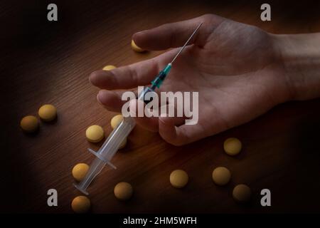 Notion de toxicomanie. Seringue de médicament et pilules à main. Banque D'Images