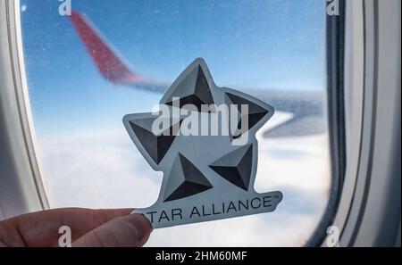 6 décembre 2021, Francfort, Allemagne. L'emblème de l'alliance aérienne Star Alliance sur le fond de la fenêtre de l'avion. Banque D'Images