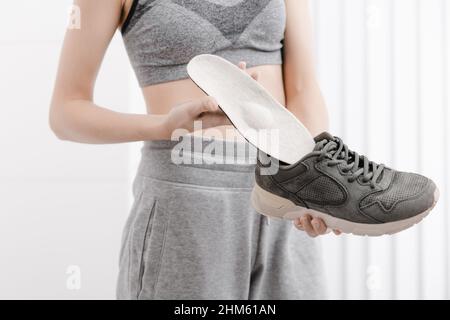 Femme mettant une semelle intérieure orthopédique dans une chaussure à la maison.Sport fille ajustement orthopédique semelle intérieure, gros plan.Bannière de soins des pieds.Correction des pieds plats Banque D'Images