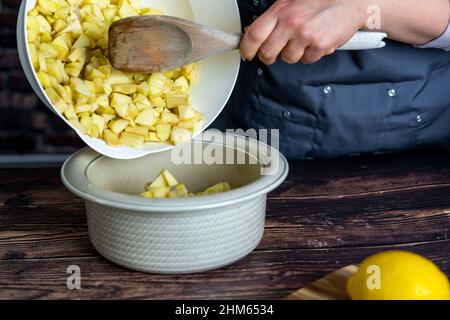 Les femmes préparant une tarte aux pommes ou une grande tarte sur fond de table en bois.Appels en petits morceaux Banque D'Images