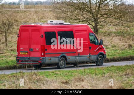 Une longue base de roues Iveco Daily 355 2,3 HPI minibus rouge conduite le long d'une route de campagne Banque D'Images