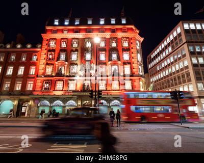 Bus et taxis passent par Fortnum et Mason grand magasin avec sa façade illuminée de Noël la nuit à Piccadilly, Londres. Banque D'Images