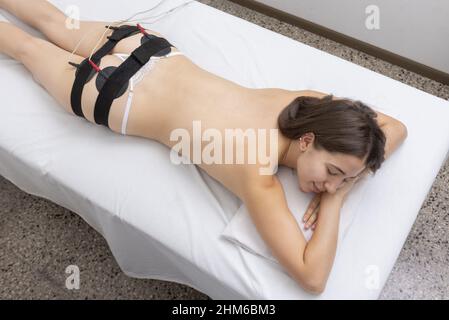 Vue en grand angle d'une femme qui s'est posée sur le lit et qui se fait soigner par mystimulation dans un salon de spa Banque D'Images