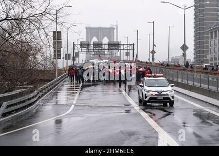 New York, NY - le 7 février 2022 : des dizaines de manifestants portant des drapeaux américains et canadiens affronte la pluie brave sur le pont de Brooklyn et se rassemblent à l'hôtel de ville contre le mandat de vaccination Banque D'Images