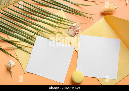 Composition avec cartes vierges, feuilles de palmier et coquillages sur fond de couleur Banque D'Images