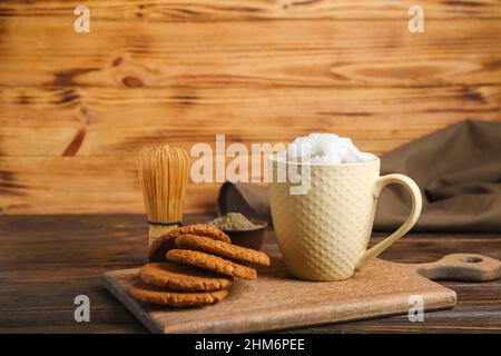 Tasse de délicieux latte de hojicha glacé et biscuits sur une table en bois Banque D'Images