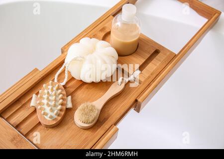 Plateau en bois avec accessoires sur baignoire blanche, gros plan Banque D'Images