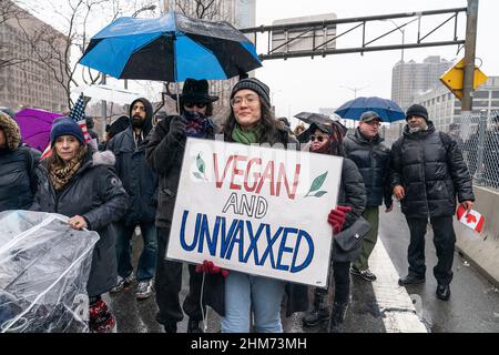 Des dizaines de manifestants portant des drapeaux américains et canadiens font braver la pluie sur le pont de Brooklyn march et se rassemblent à l'hôtel de ville contre le mandat de vaccination. Les employés de la ville ont été informés que tous les sujets non entièrement vaccinés seront mis fin en février 11. Les manifestants ont été rejoints par des membres du New York Freedom Rally. Beaucoup portaient des drapeaux américains ainsi que des drapeaux canadiens pour appuyer les camionneurs qui ont protesté de la même façon dans la capitale du Canada, Ottawa. Une femme porte le signe Vega et non vacciné en référence au maire Adams qui est vegan. (Photo de Lev Radin/Pacific Press) Banque D'Images