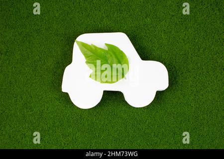 Gros plan d'une voiture blanche avec une feuille verte sur fond d'herbe. Concept de transport de voiture écologique. Économie d'environnement économie d'énergie. Banque D'Images