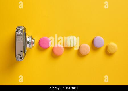 Théorie des couleurs et concept de photographie. Des macarons colorés conçus comme des ondes lumineuses avec un appareil photo vintage. Banque D'Images