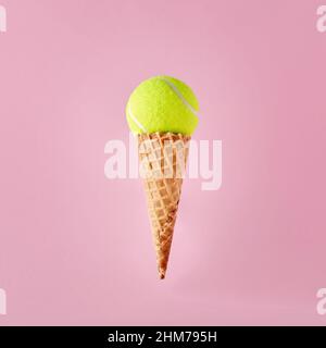 Balle de tennis sur cône de glace sur fond rose. Concept minimaliste de sport, de divertissement et de loisirs. Banque D'Images