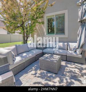 Nuages carrés Puffy au coucher du soleil patio extérieur avec canapé tissé et chaise longue près de l'arbre Banque D'Images