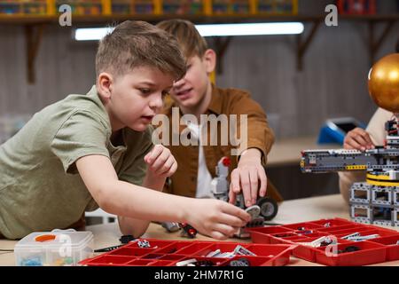 Portrait de deux jeunes garçons construisant des robots tout en appréciant la classe d'ingénierie à l'école, l'espace de copie Banque D'Images