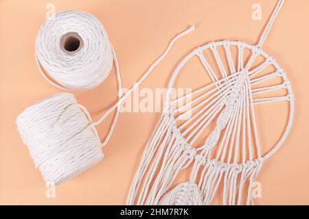 Rouleaux de fil de coton macrame et objet mural fini sur fond beige Banque D'Images