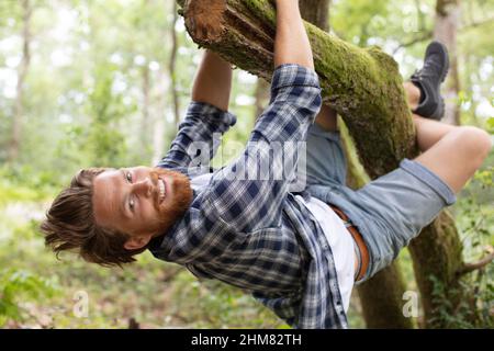 le jeune homme escalade un arbre Banque D'Images