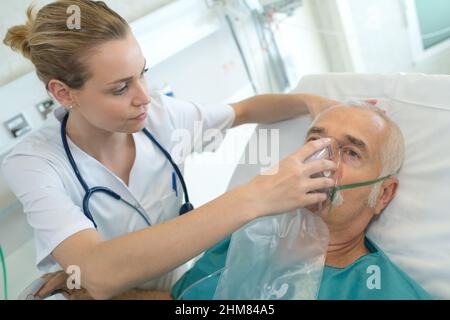 femme médecin appliquant un masque à oxygène sur un patient âgé Banque D'Images