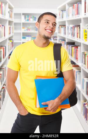Étudiant à la recherche regarder bibliothèque livres format portrait sourire heureux jeune homme personnes livre Banque D'Images