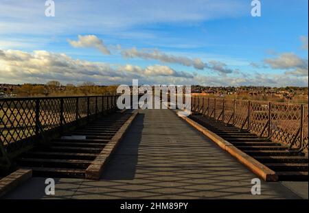 Sur un hiver lumineux mais frais et gréezy matin les marcheurs sont très petits dans la distance sur le long pont du géant de fer, le viaduc de Bennerley. Banque D'Images