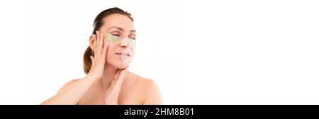 une femme d'âge moyen pendant les procédures cosmétiques touche doucement son visage. Banque D'Images