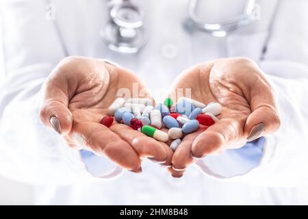 Détail d'un médecin tenant la main de diverses pilules colorées dans les deux mains. Banque D'Images