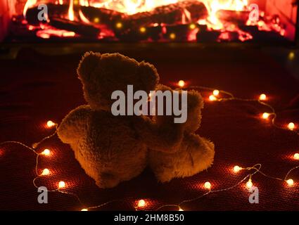 deux ours en peluche s'embrasent et regardent la flamme de la cheminée. Saint-Valentin, Banque D'Images