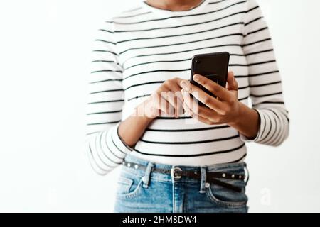 Les technologies intelligentes vous permettent de garder votre vie sociale en vie. Prise de vue rognée d'une femme utilisant un smartphone sur un arrière-plan de studio blanc. Banque D'Images