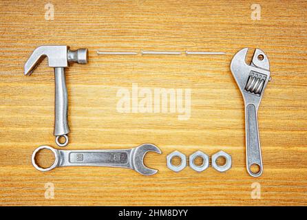 Copies miniatures d'outils à main et de fixations essentiels disposées sur une table en bois. Concept de maintenance et de réparation. Banque D'Images