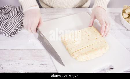 Étape par étape. Coupe de fudge de canne à sucre fait maison sur un tableau de découpe blanc. Banque D'Images