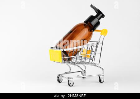Bouteille cosmétique avec distributeur dans un chariot sur fond blanc. Achats en ligne pour les cosmétiques Banque D'Images