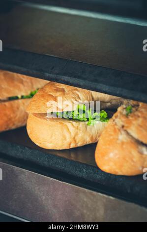 Sandwichs en préparation. Petits pains frais avec garniture sur le gril plancha. Banque D'Images