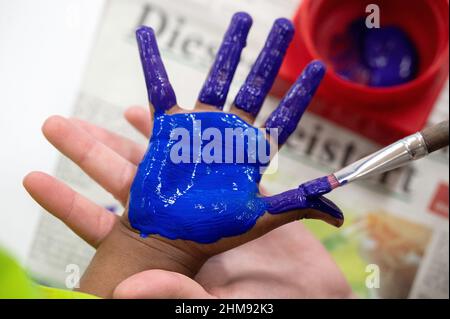 PRODUCTION - 02 février 2022, Hessen, Darmstadt : un enseignant peint la main d'un enfant avec de la peinture au doigt dans un centre de garderie. Photo: Sebastian Gollnow/dpa Banque D'Images