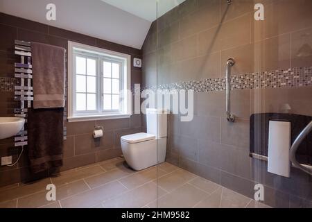 Burrough Green, Suffolk - juillet 12 2018 : salle de douche moderne et luxueuse, wc avec murs carrelés et cabine de douche lambrissée en verre Banque D'Images